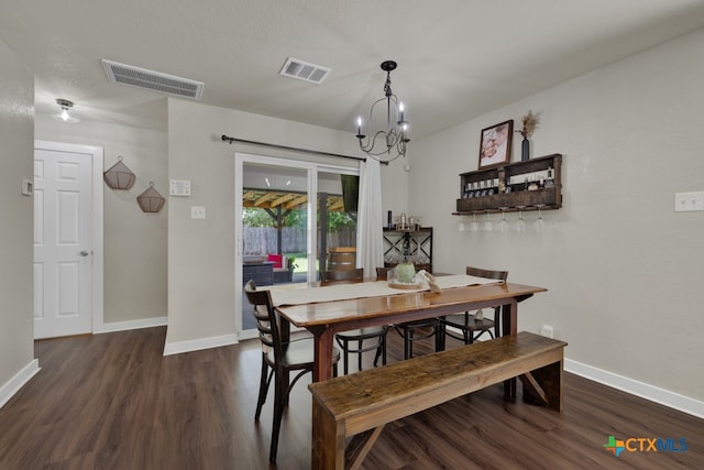 dining area featuring dark wood-type flooring and an inviting chandelier