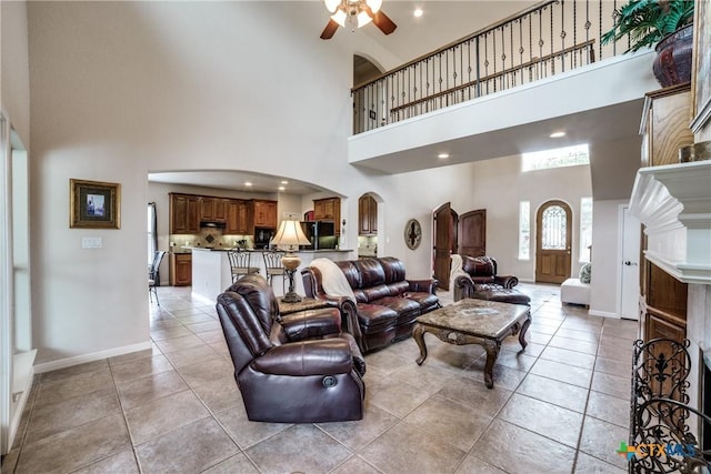 living room with light tile patterned floors, a towering ceiling, and ceiling fan