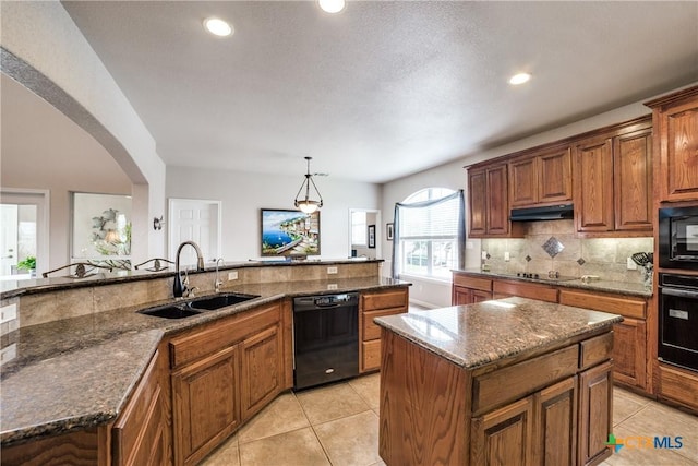 kitchen featuring pendant lighting, a center island, sink, and black appliances