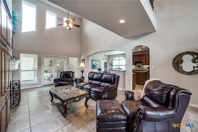 living room featuring french doors, ceiling fan, light tile patterned flooring, and a towering ceiling