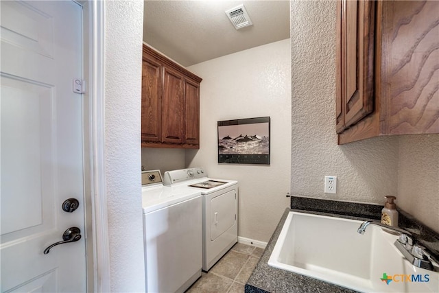 clothes washing area with sink, washer and clothes dryer, and cabinets