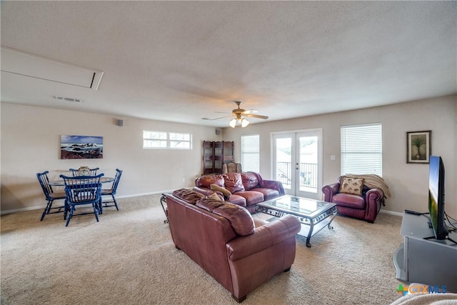 carpeted living room with ceiling fan, french doors, and a textured ceiling