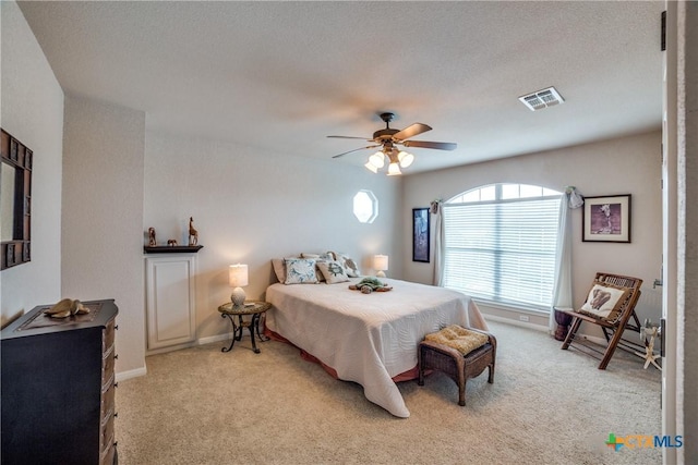 bedroom featuring light carpet, a textured ceiling, and ceiling fan