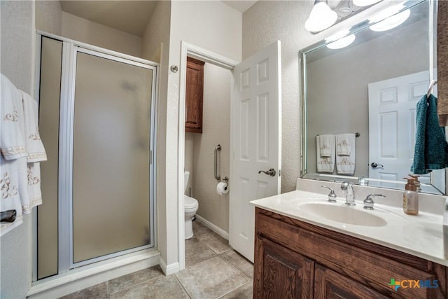 bathroom with vanity, tile patterned floors, a shower with door, and toilet