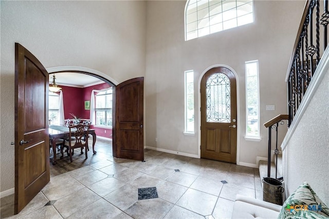 tiled entryway featuring crown molding and a towering ceiling