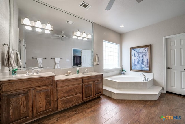 bathroom with hardwood / wood-style flooring, ceiling fan, vanity, and a bathtub