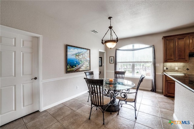 dining space with a textured ceiling and light tile patterned floors