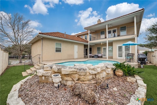 rear view of house with ceiling fan, a fenced in pool, a patio, and a balcony