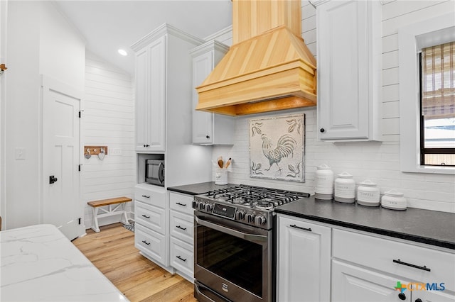 kitchen with vaulted ceiling, decorative backsplash, white cabinets, custom range hood, and appliances with stainless steel finishes