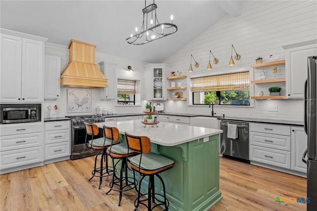 kitchen with appliances with stainless steel finishes, white cabinetry, a kitchen island, and a wealth of natural light