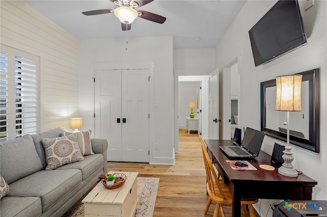 living room featuring light hardwood / wood-style flooring, ceiling fan, and wooden walls