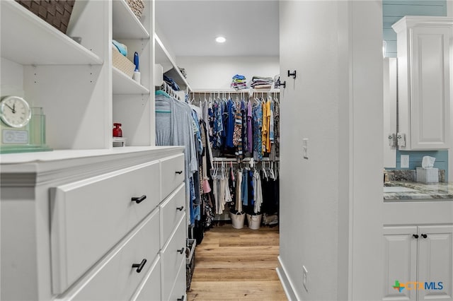 walk in closet with light hardwood / wood-style flooring