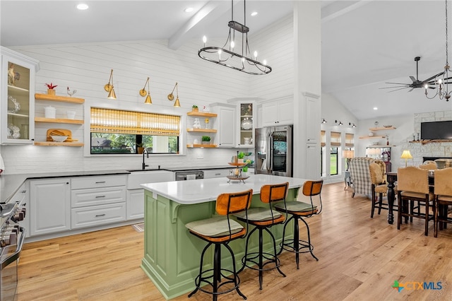 kitchen featuring stainless steel appliances, light hardwood / wood-style flooring, high vaulted ceiling, a breakfast bar, and white cabinets