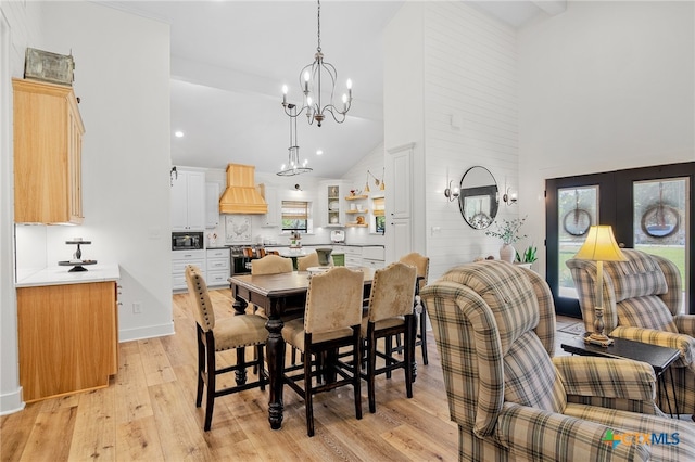 dining space featuring a chandelier, high vaulted ceiling, and light hardwood / wood-style flooring