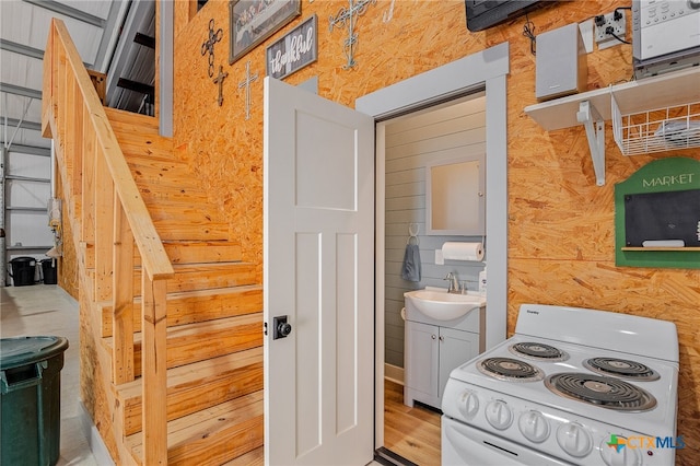 kitchen featuring sink, hardwood / wood-style flooring, white electric stove, and wood walls