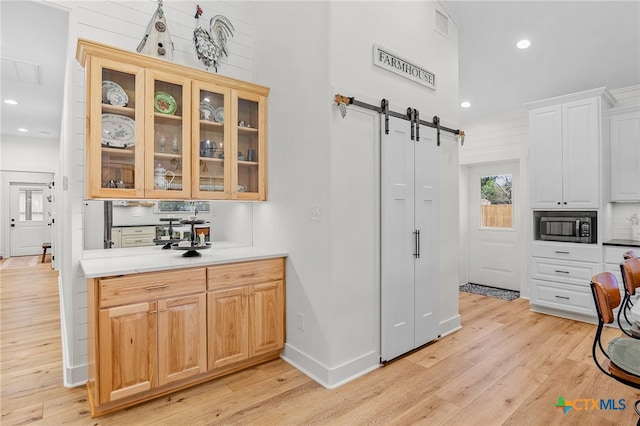 kitchen featuring a barn door, light wood-type flooring, and a towering ceiling