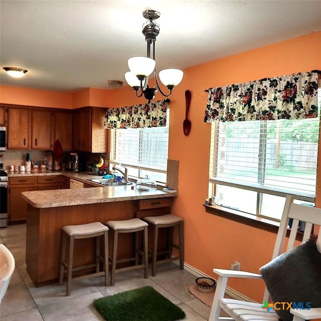 kitchen featuring kitchen peninsula, sink, decorative light fixtures, and light tile patterned flooring