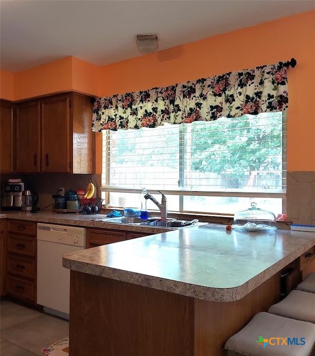 kitchen featuring dishwasher, decorative backsplash, kitchen peninsula, and sink