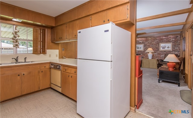 kitchen with brick wall, sink, white appliances, and light carpet