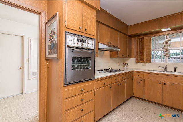 kitchen with white gas cooktop, stainless steel oven, sink, and backsplash