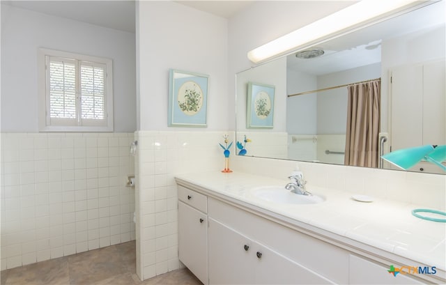 bathroom with tile walls, walk in shower, vanity, and tile patterned floors