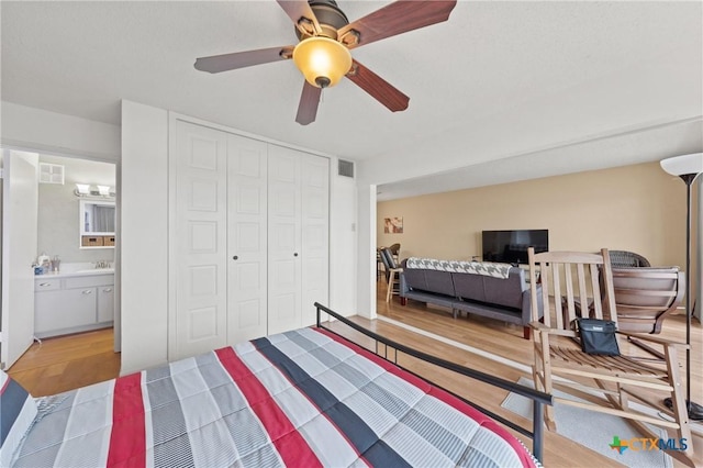 bedroom with light wood finished floors, a closet, visible vents, ensuite bathroom, and ceiling fan