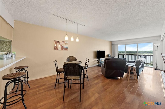 dining area with baseboards, a textured ceiling, track lighting, and wood finished floors