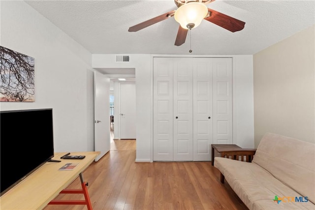 home office featuring a ceiling fan, visible vents, a textured ceiling, and wood finished floors