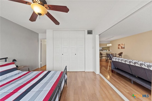 bedroom with light wood-style floors, a closet, visible vents, and ceiling fan