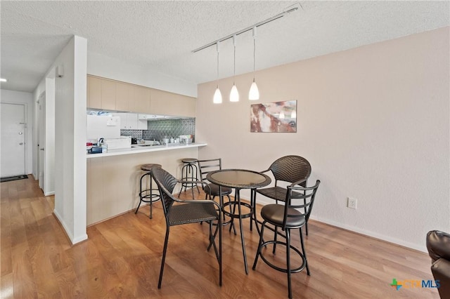 dining space with light wood-style flooring and a textured ceiling