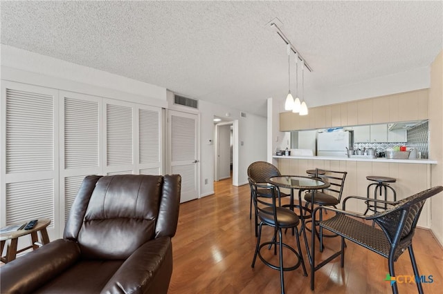 dining area with a textured ceiling, wood finished floors, and visible vents