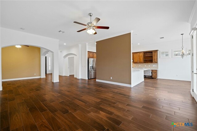 815 Lost Maples Trl, Georgetown, TX 78633 - unfurnished living room featuring a ceiling fan, arched walkways, dark wood-style floors, ornamental molding, and baseboards