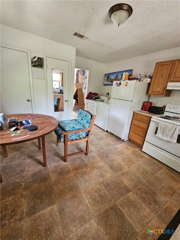 915 Dryden Ave, Copperas Cove, TX 76522 - kitchen featuring under cabinet range hood, white appliances, a textured ceiling, washer / dryer, and light countertops