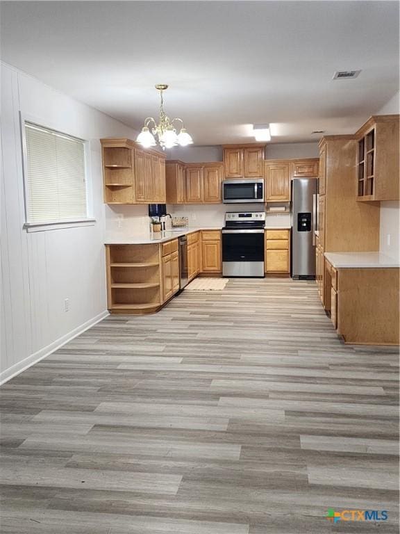 kitchen with pendant lighting, sink, appliances with stainless steel finishes, light hardwood / wood-style floors, and a chandelier