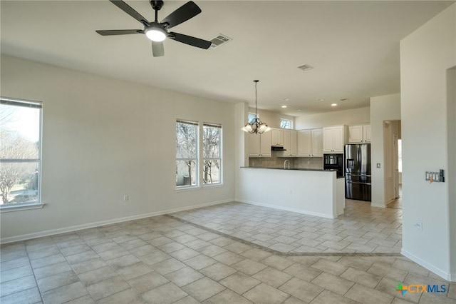 kitchen with hanging light fixtures, stainless steel fridge, dark countertops, tasteful backsplash, and open floor plan