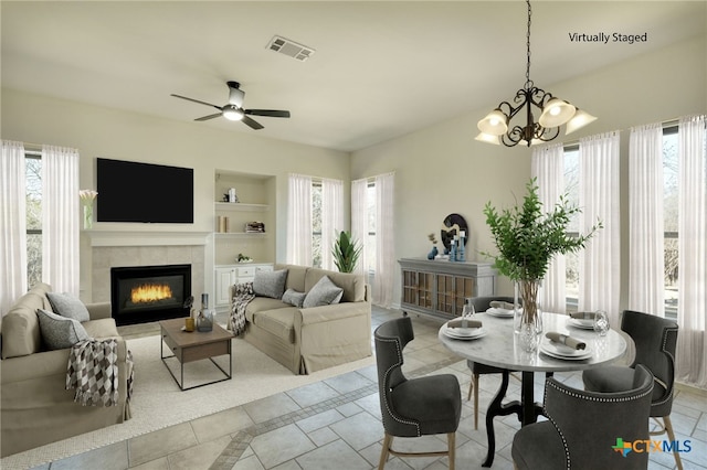 dining area featuring a tiled fireplace, visible vents, plenty of natural light, and built in shelves