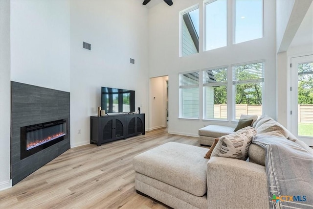 288 Smithsonian Ln, Kyle, TX 78640 - living room with a ceiling fan, wood finished floors, a glass covered fireplace, baseboards, and visible vents