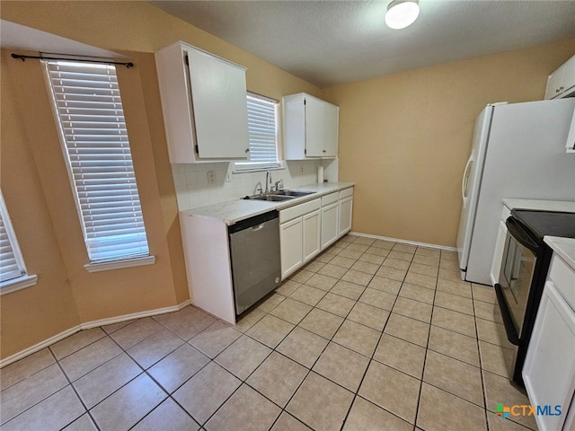 kitchen with sink, white cabinets, stainless steel dishwasher, light tile patterned floors, and black / electric stove