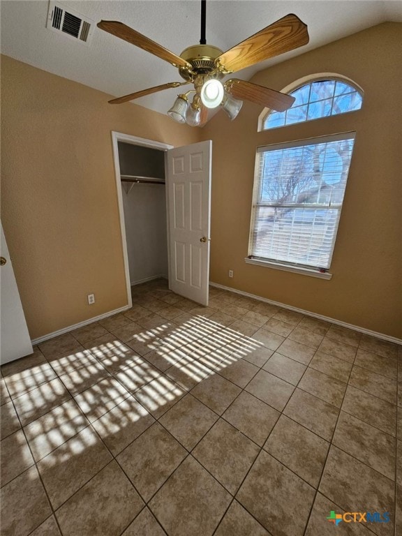 unfurnished bedroom featuring light tile patterned flooring, vaulted ceiling, ceiling fan, and a closet