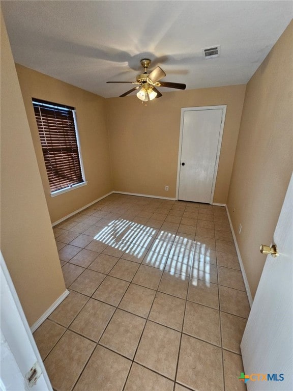 tiled spare room with ceiling fan