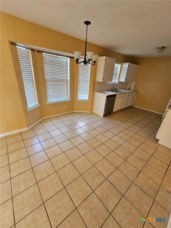 kitchen featuring white cabinetry, a chandelier, hanging light fixtures, light tile patterned floors, and stainless steel dishwasher