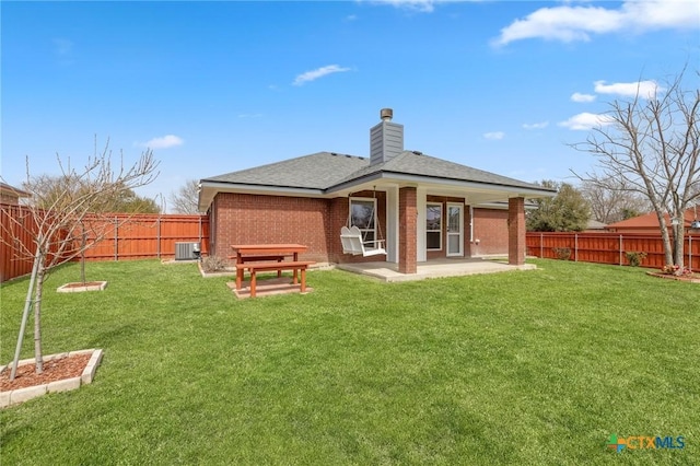 back of property featuring brick siding, a lawn, cooling unit, and a fenced backyard