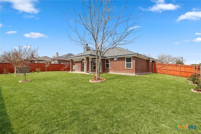 back of property with brick siding, a yard, a chimney, a patio area, and a fenced backyard