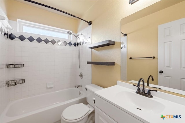 full bath with tub / shower combination, a textured wall, vanity, and toilet