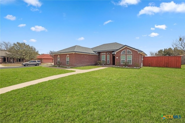 ranch-style house featuring a front yard, fence, and brick siding