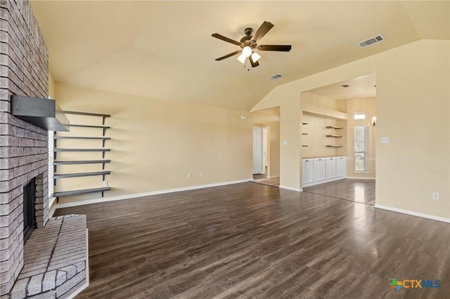 unfurnished living room with lofted ceiling, a fireplace, wood finished floors, and visible vents