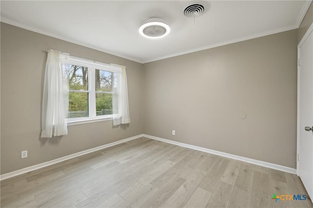 empty room with light wood finished floors, visible vents, baseboards, and ornamental molding