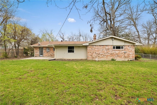 rear view of property with fence, brick siding, and a lawn