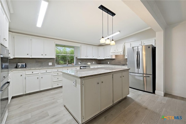 kitchen featuring decorative backsplash, a kitchen island, appliances with stainless steel finishes, and light wood-style flooring