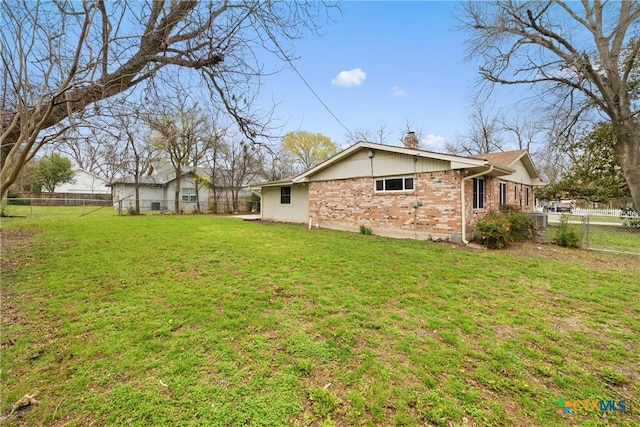 view of home's exterior featuring a yard, brick siding, a fenced backyard, and a chimney